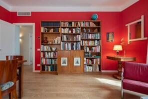 Um quarto com uma grande estante de madeira, parede vermelha e chão de madeira.