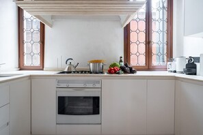 A kitchen with a built-in oven, a stove, and a window with a geometric pattern. - Ca' Nova (Venezia)