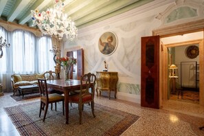 A dining area with a table, chairs, a chandelier, and a sofa. - Ca' Nova (Venezia)