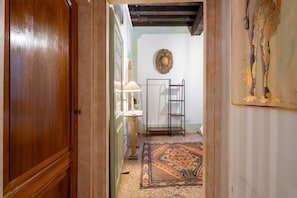 A hallway with a wooden door, a lamp, a patterned rug, and a wall with a decorative plate. - Ca' Nova (Venezia)