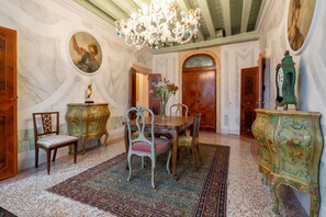 A room with a dining table, chairs, a chandelier, and a clock. - two bedrooms apartment in San Marco (Venezia)