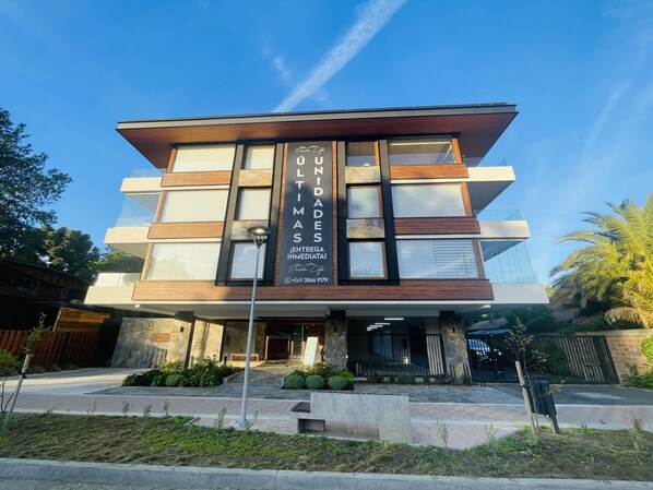 A modern building with a large sign advertising 'UNIDOS' and a contact number. - Apartamento a Estrenar, Céntrico, Cerca de Playa Grande. Cochera. Equipado Full (Cautin)