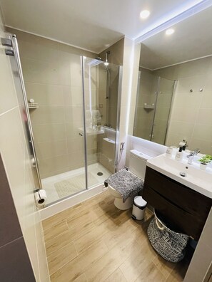 A modern bathroom with a glass-enclosed shower, a white sink, and a dark-toned vanity. - Apartamento a Estrenar, Céntrico, Cerca de Playa Grande. Cochera. Equipado Full (Cautin)