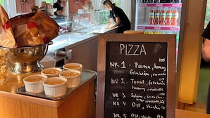 En disk där man beställer pizza, med en tavla där de olika pizzorna och priserna står uppskrivna.