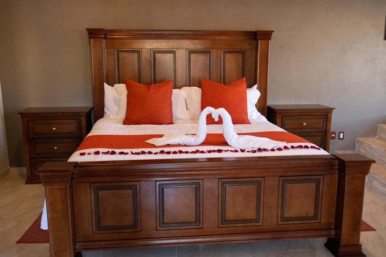 A large wooden bed with a headboard, two nightstands, and a decorative swan made of towels on the bed.