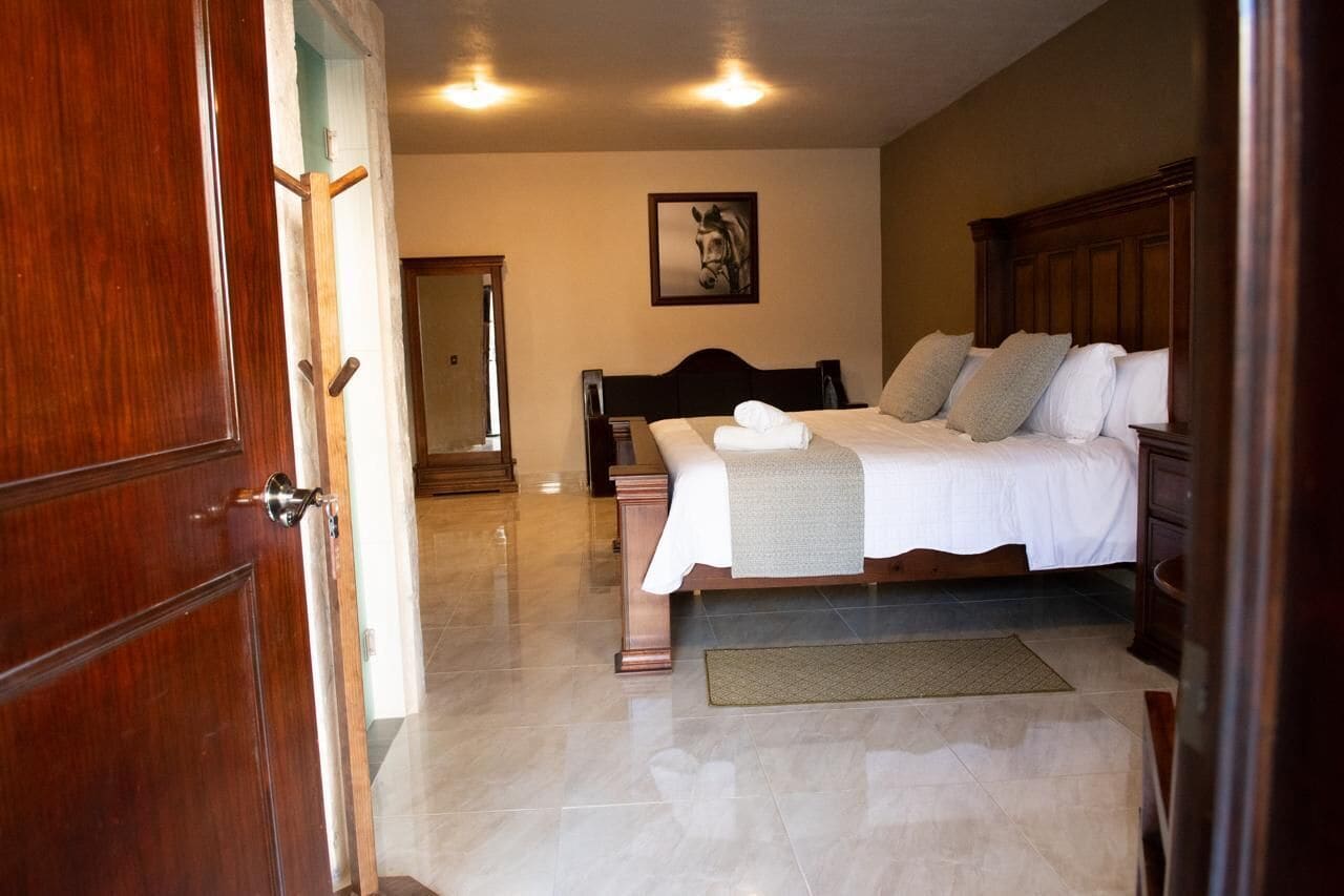 A bedroom with a bed, a wooden headboard, a bedside table, a mirror, and a framed picture on the wall.