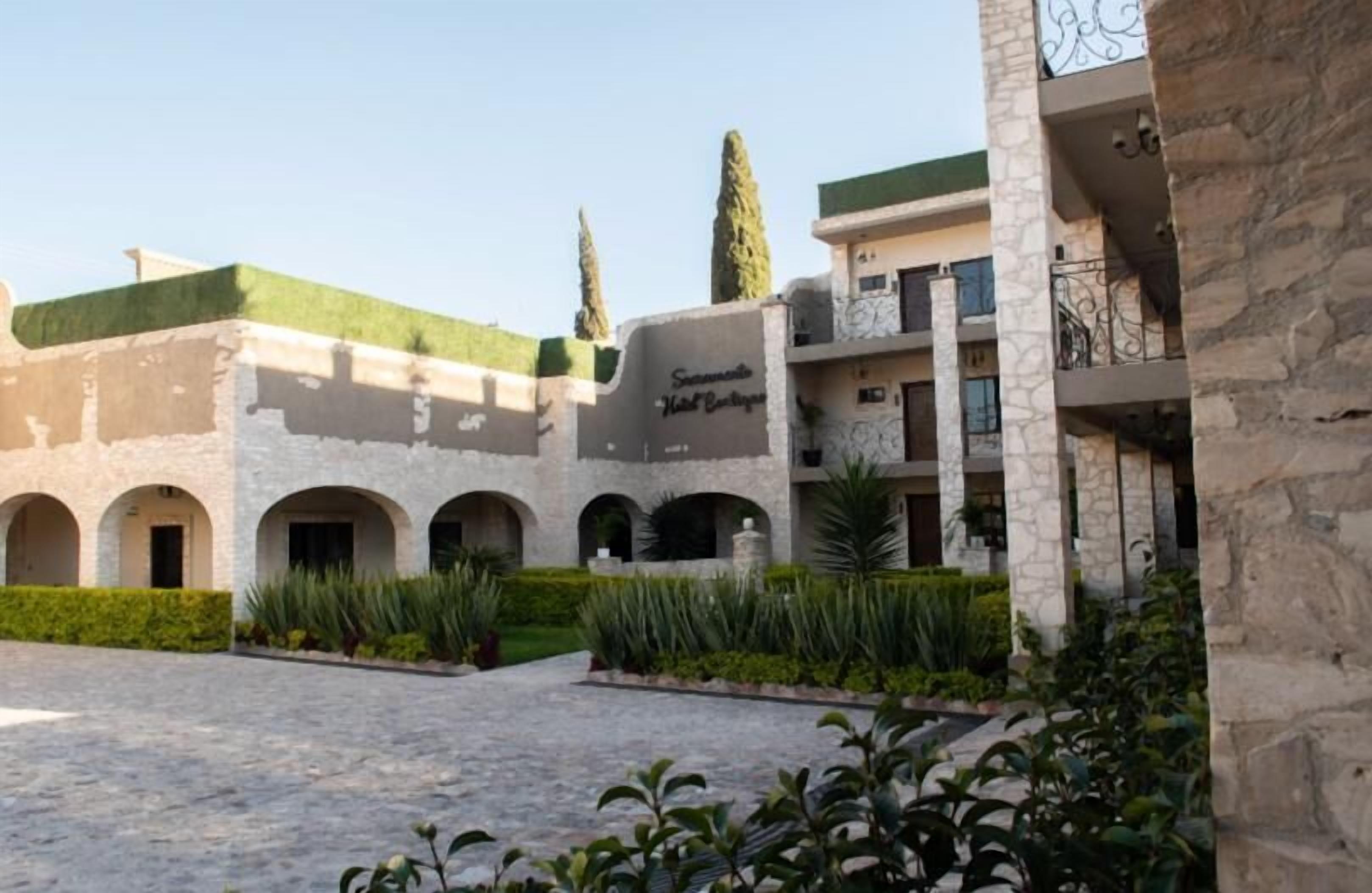 A courtyard with a stone building, arched doorways, and a sign reading "Sonsal Hotel Boutique."