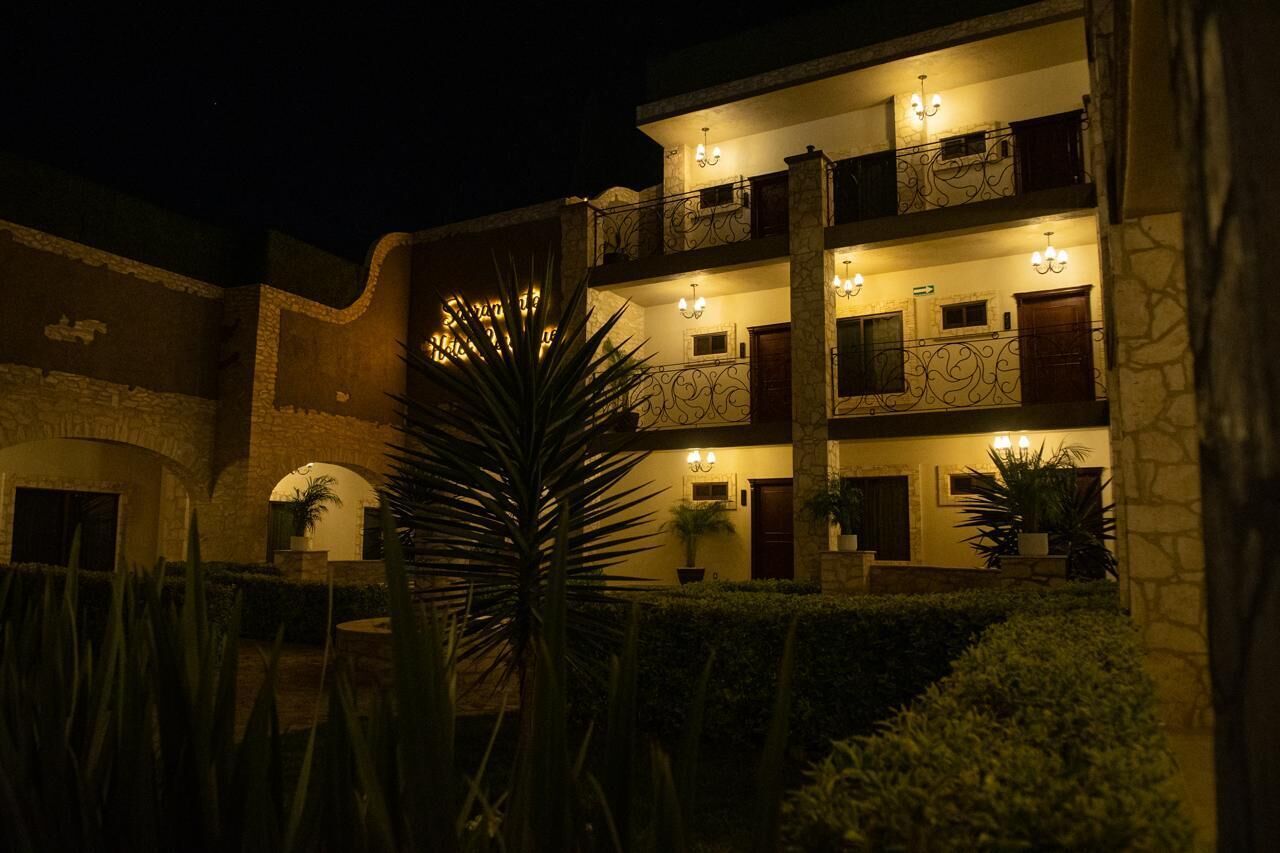 A multi-story building with balconies, outdoor lighting, and a well-maintained garden.