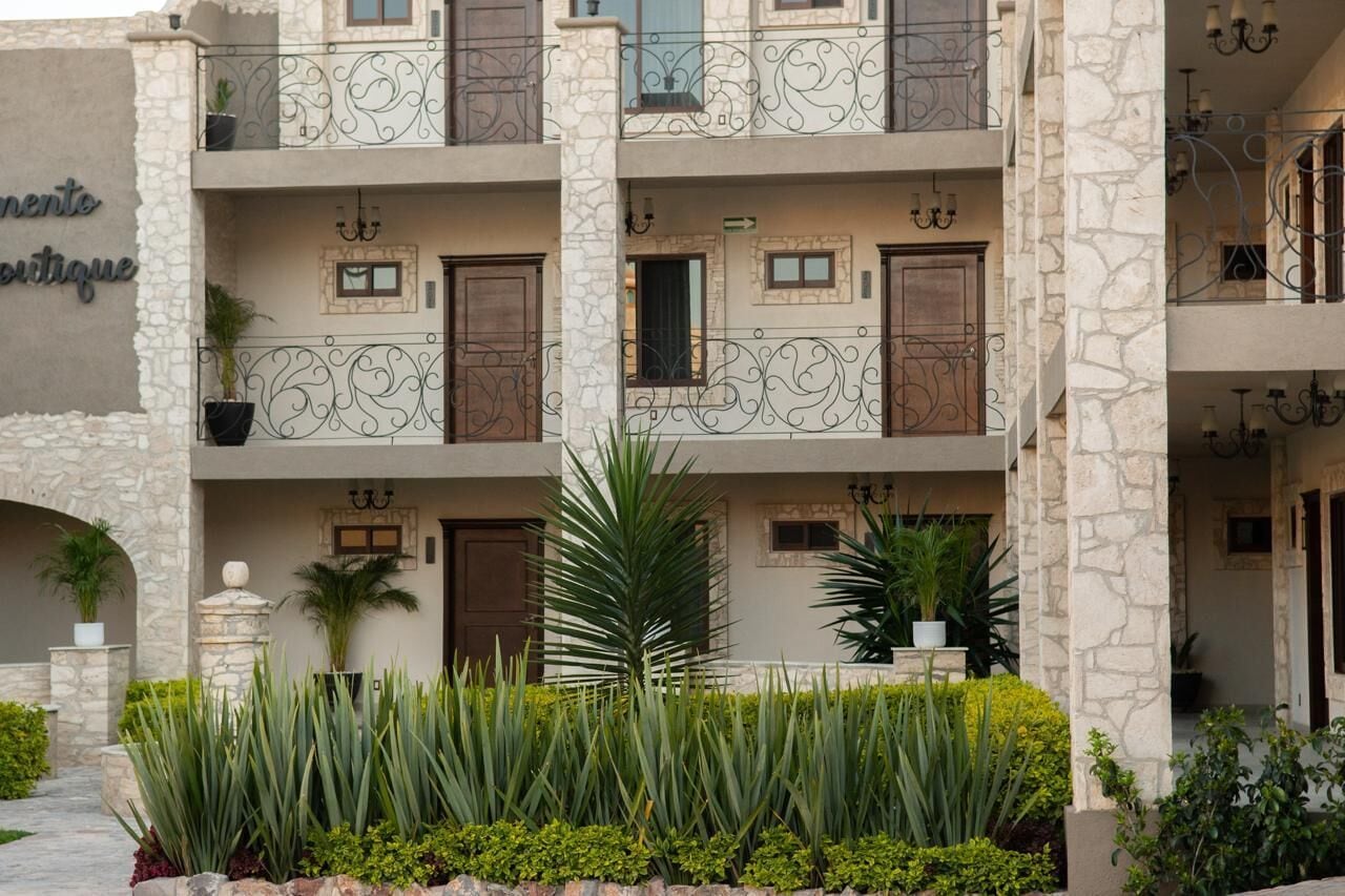 A multi-story building with balconies, stone facade, and potted plants.