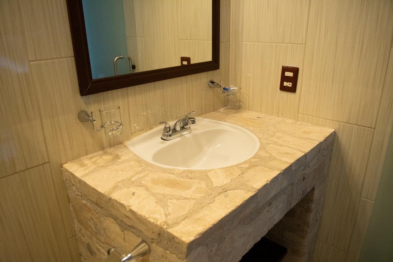 A bathroom with a stone sink, a mirror, and a towel rack.