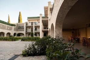 A hotel courtyard with stone arches, a central open space, and a dining area with tables and chairs. - Sacramento Hotel Boutique  (Ezequiel Montes)