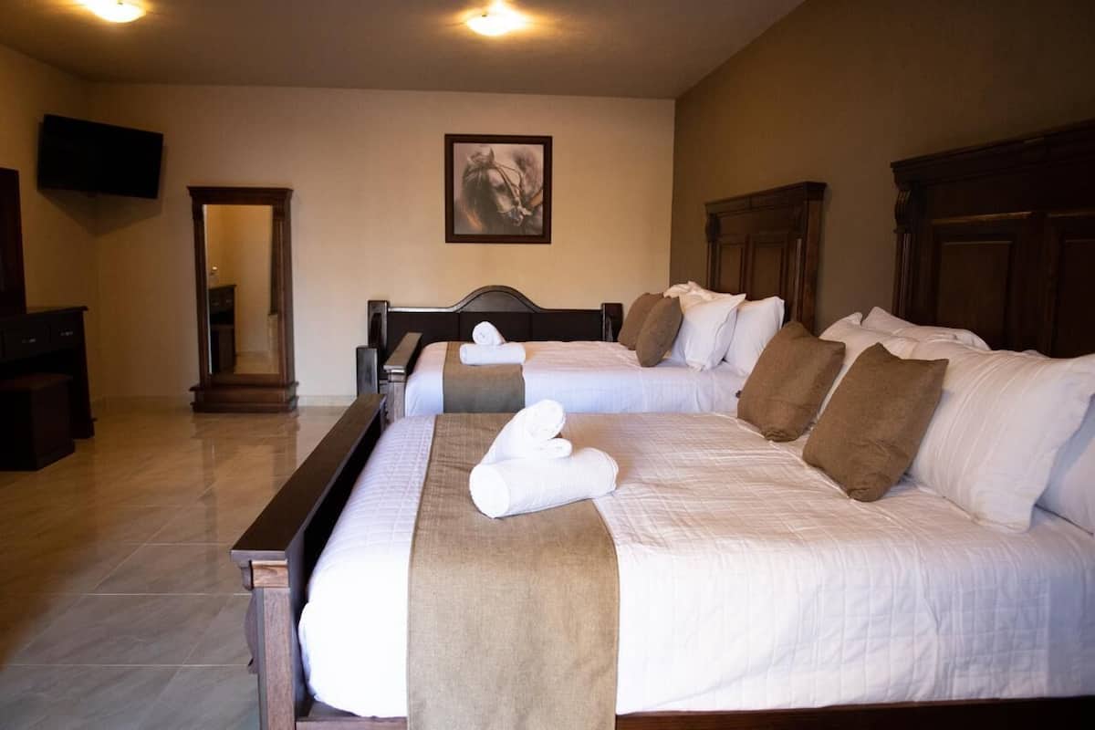 A hotel room with two beds, a wooden headboard, a flat-screen TV, and a framed picture on the wall.