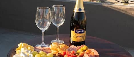 A table with a bottle of Riunite, two glasses, and a variety of cheeses and meats on a wooden table with a sign reading "Sacramento Hotel Boutique".