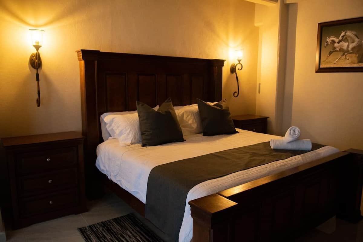A neatly made bed with a wooden headboard, two bedside tables, and a wall-mounted light fixture.
