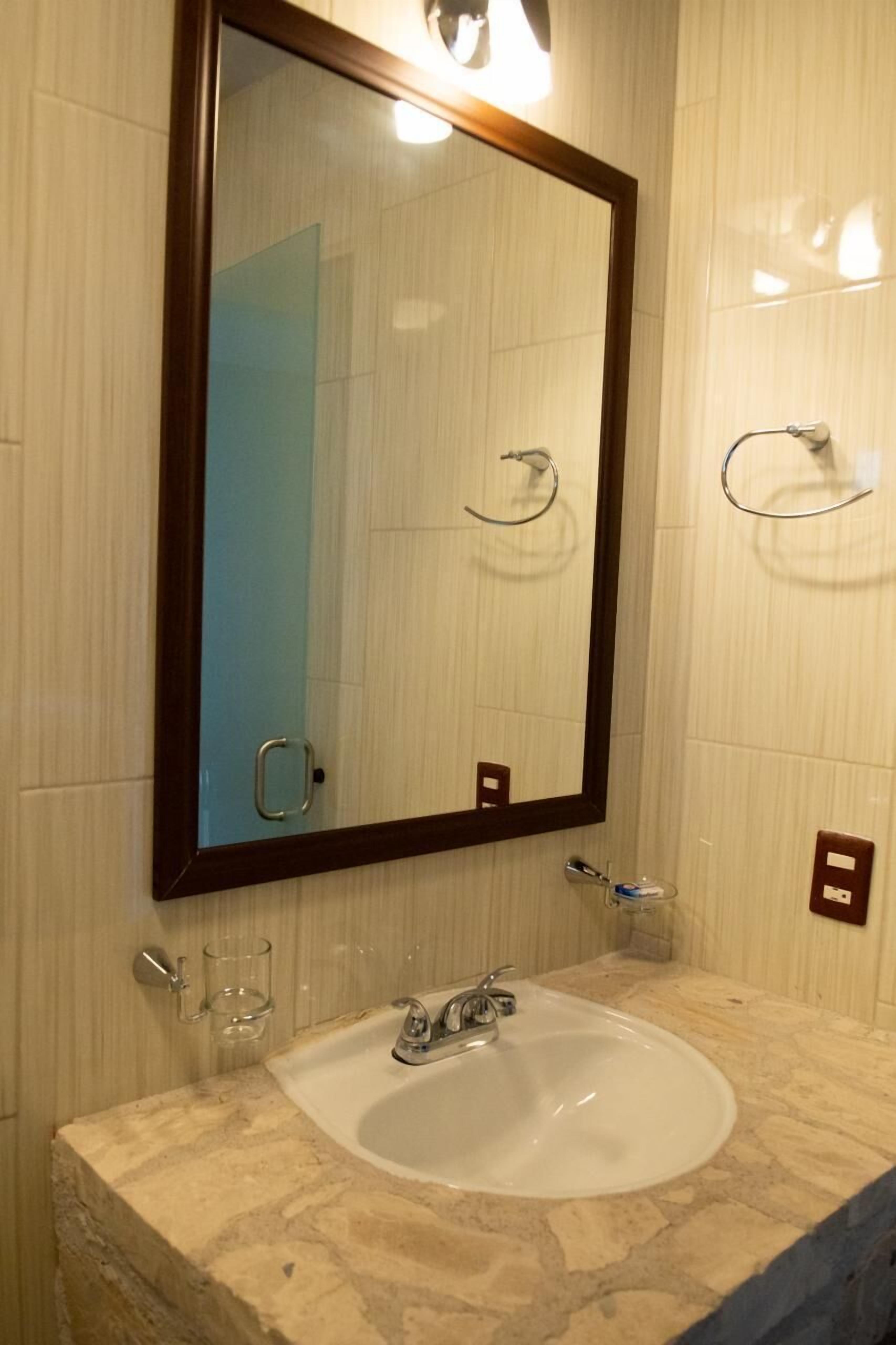 A bathroom with a white sink, a mirror, and a towel rack.