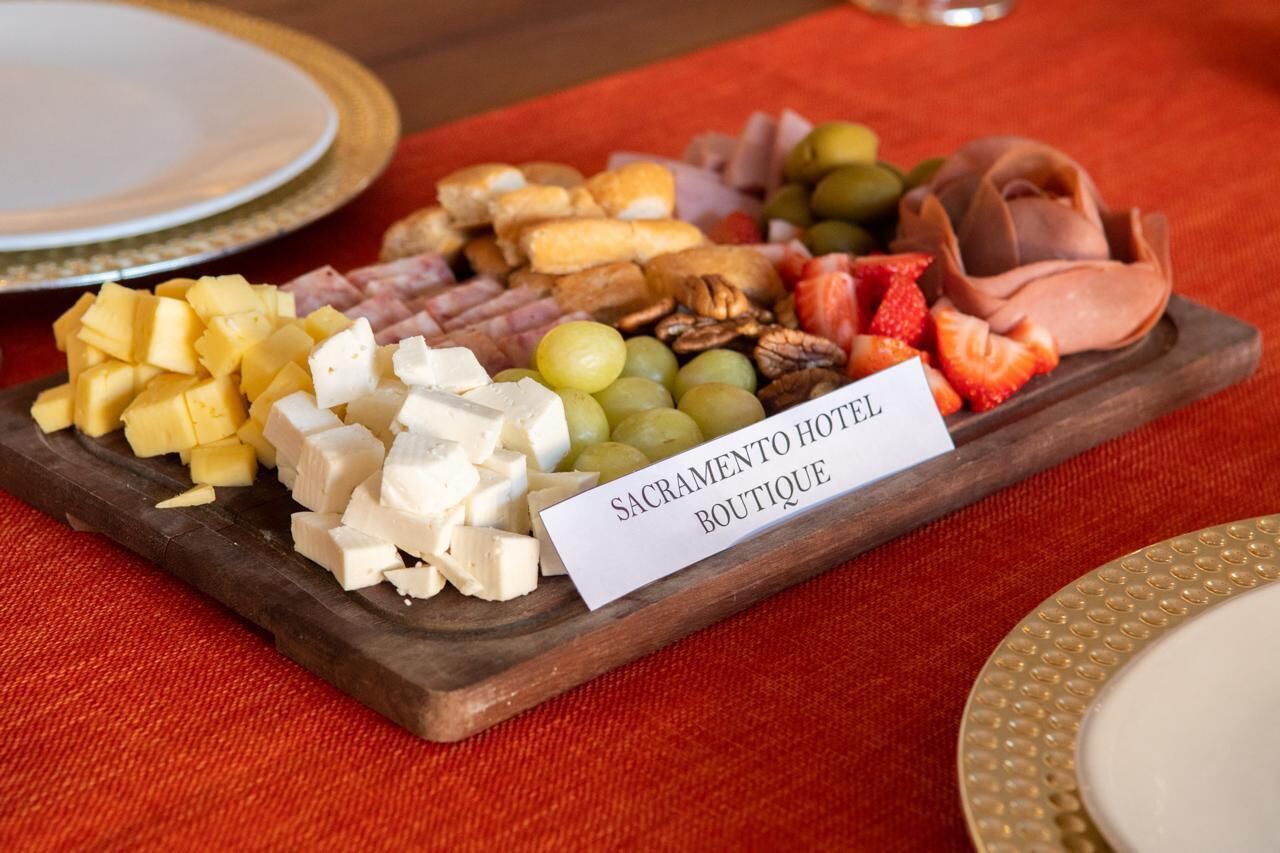 A wooden board with a variety of cheeses, fruits, and nuts, labeled "Sacramento Hotel Boutique."