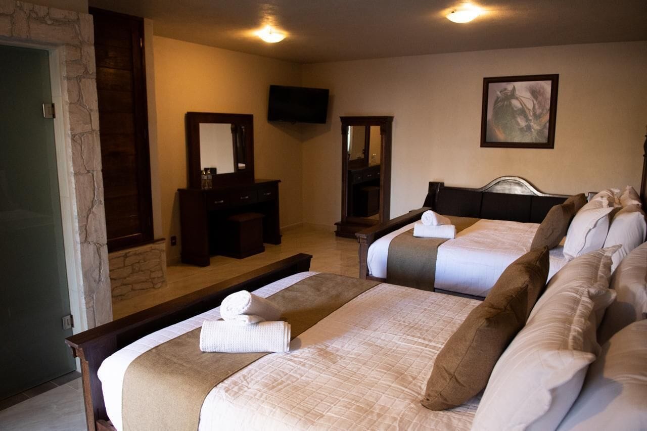 A hotel room with two beds, a TV, a mirror, and a painting on the wall.