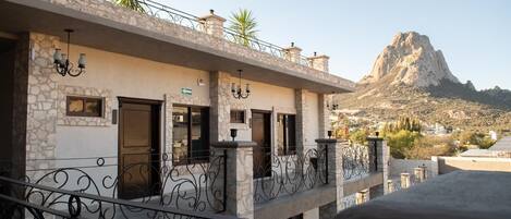 A building with stone walls, balconies with wrought iron railings, and a view of a mountain.