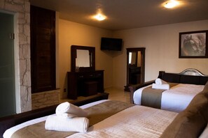 A hotel room with two beds, a TV, a mirror, and a stone wall. - Sacramento Hotel Boutique  (Ezequiel Montes)