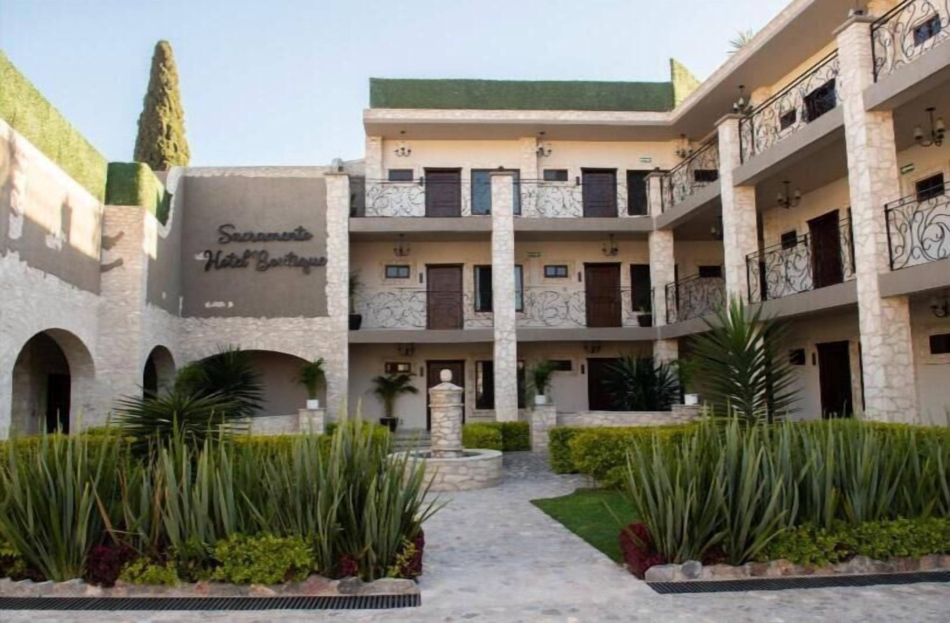 A hotel with a central courtyard, multiple balconies, and a sign reading "Sacramento Hotel Boutique."