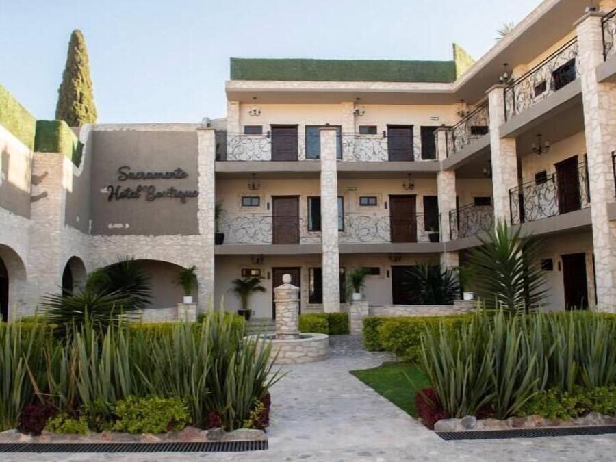 A hotel with a central courtyard, multiple balconies, and a sign reading "Sacramento Hotel Boutique."