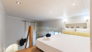 A hotel room with a large bed, a wooden floor, a glass door, and a white ceiling. - Santa Catarina Harmony by Homing (Lisbon)