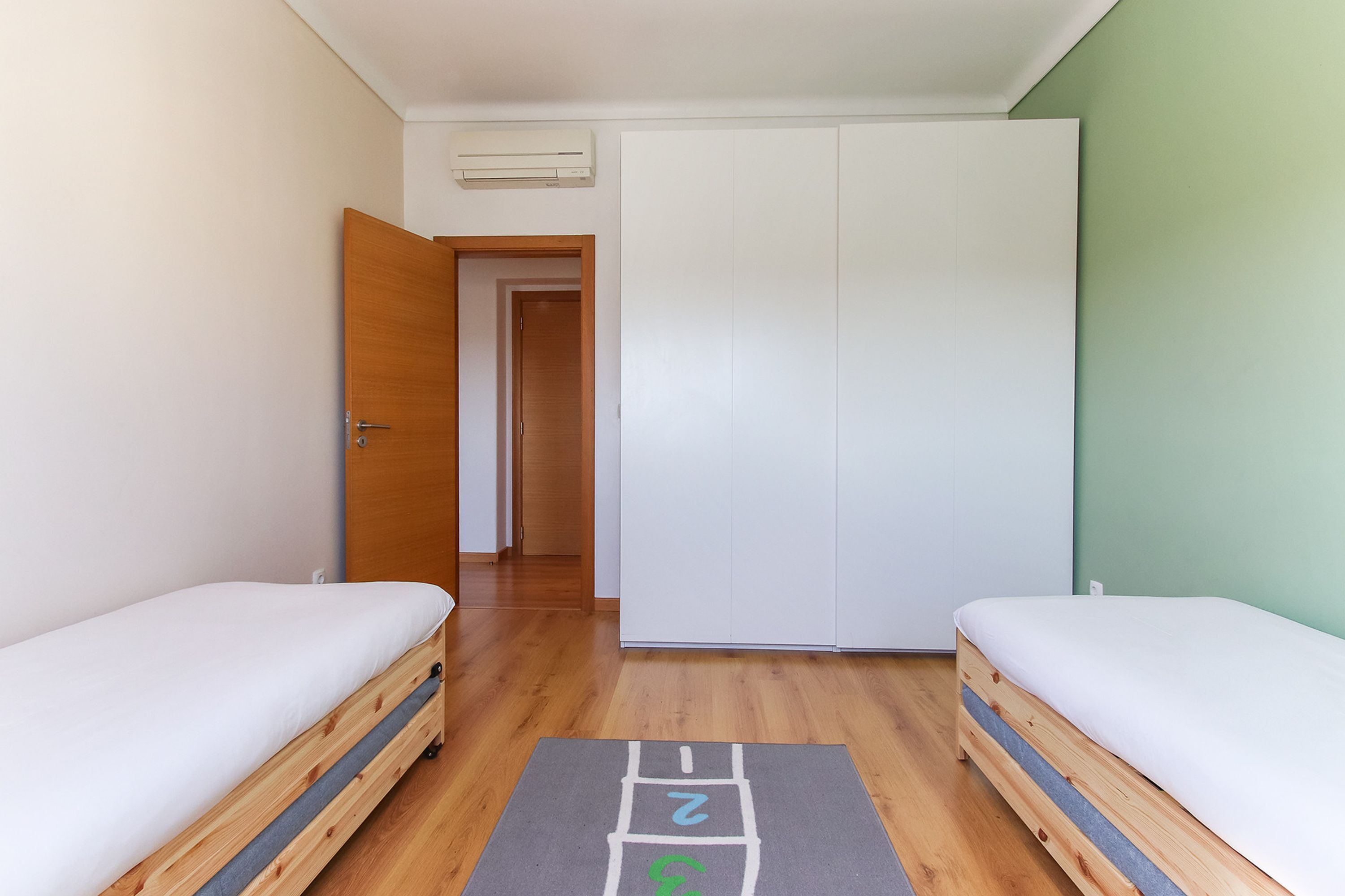 Una habitación con dos camas de madera, un armario y un pasillo que lleva a otra habitación.