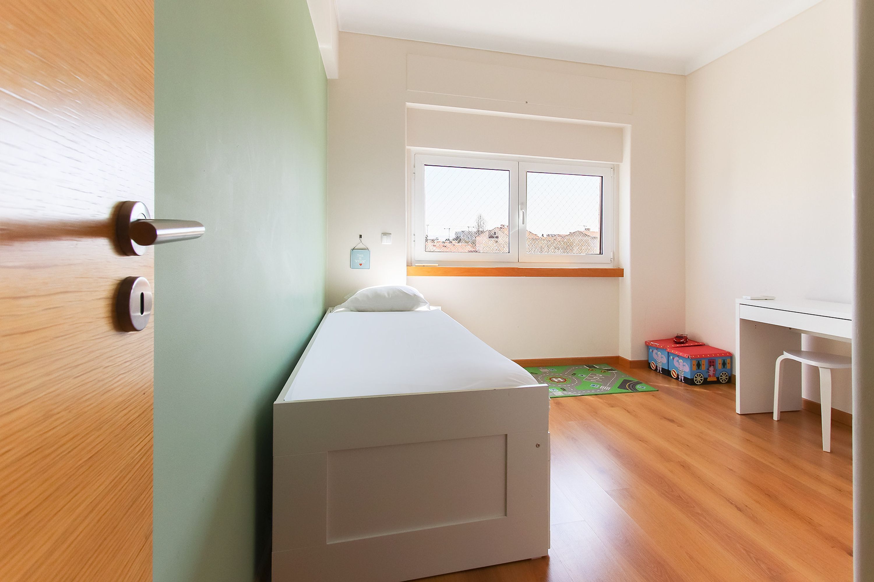 Un dormitorio con cama, escritorio y ventana.