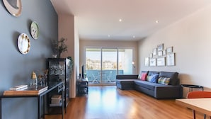A modern living room with a sofa, a dining table, and a bookshelf. - Olivais Balcony by Homing (Lisbon)