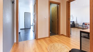 A modern interior with wooden floors, a round woven rug, and a dining area with chairs and a table. - Olivais Balcony by Homing (Lisbon)