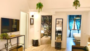 Uma sala de estar moderna com uma televisão de tela plana, um sofá, uma mesa de centro e um espaço de jantar com mesa e cadeiras.