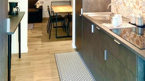 Cozinha moderna com armários escuros, mesa de jantar de madeira e luminária pendente.