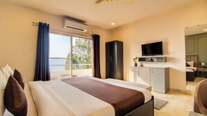 A hotel room with a bed, a TV, a wardrobe, and a bathroom mirror. - Harmony Palace (Mahabaleshwar)