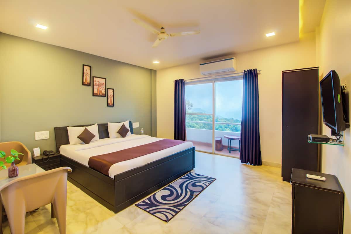 A hotel room with a bed, a desk, a chair, a TV, and a balcony with a view.