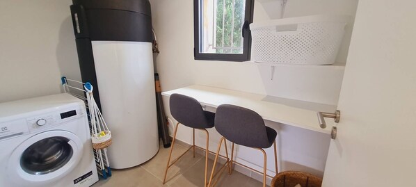 A compact laundry room with a washing machine, a drying machine, and a small bar stool area.