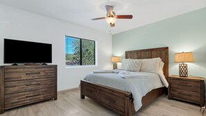 A bedroom with a bed, wooden nightstands, a ceiling fan, a TV, and a window with blinds. - Sedona Eve

 (Sedona)