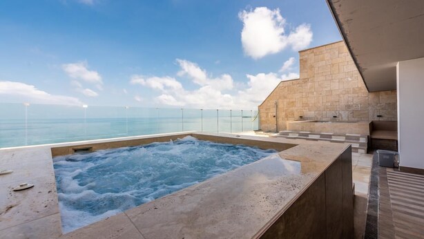 A hot tub with a view of the ocean, a stone wall, and a modern outdoor seating area. - Cartagena Morros Beach and Sea (Cartagena)