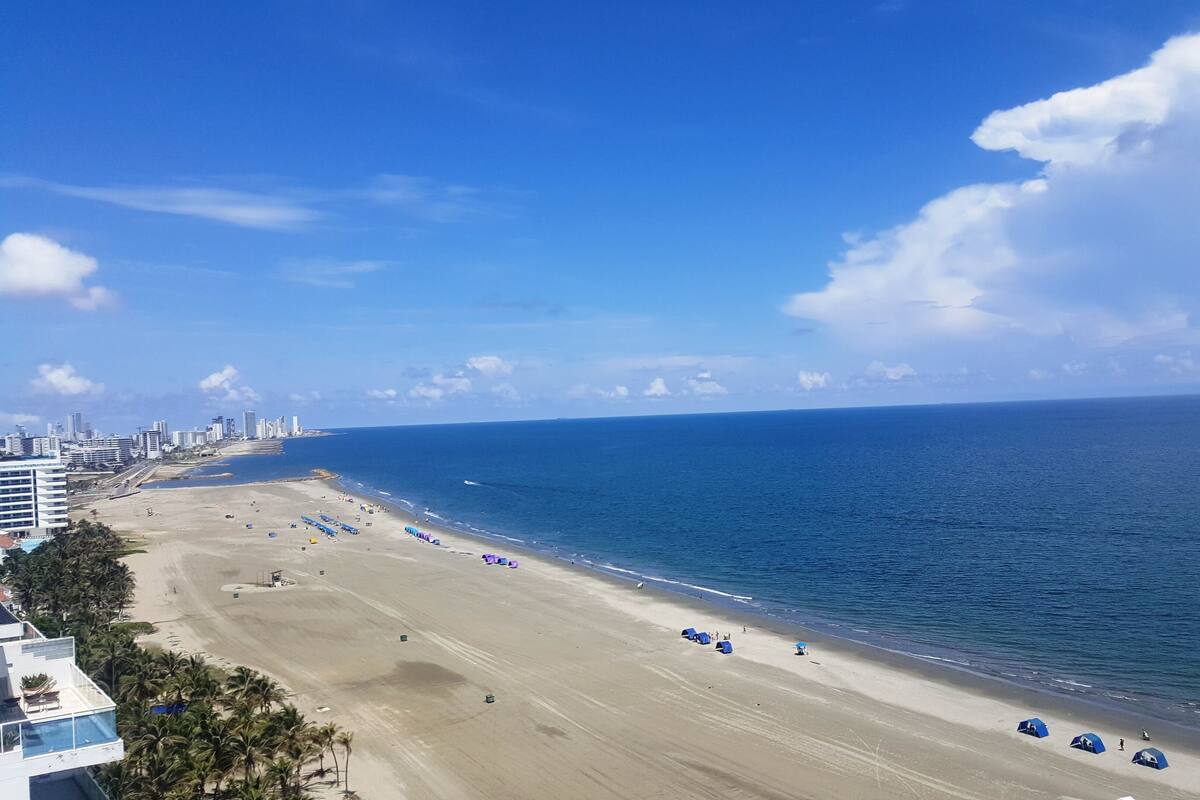 A beach with a clear view of the ocean and a city skyline in the background.