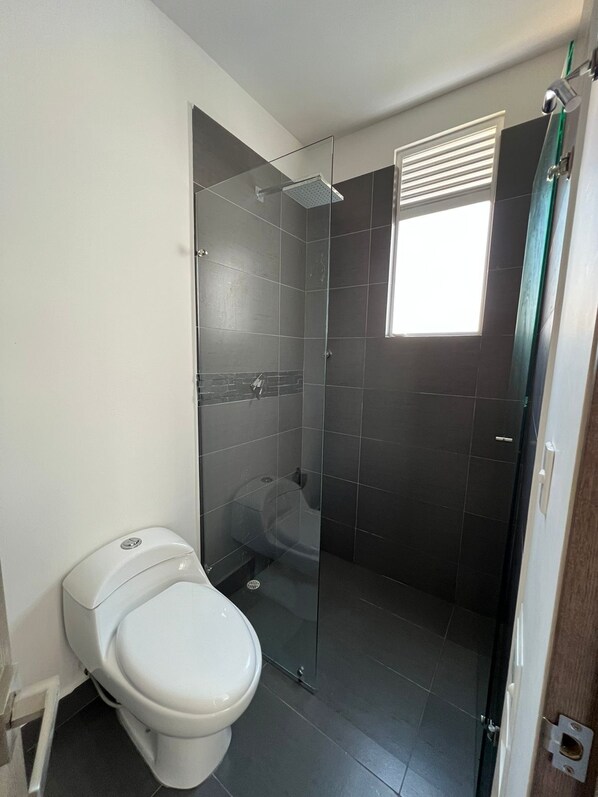 A modern bathroom with a toilet, a glass-enclosed shower, and a bathtub.