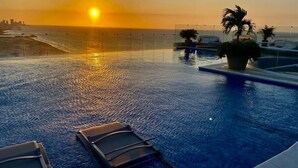 A swimming pool with a sunset view, lounge chairs, and palm trees. - Cartagena Morros Beach and Sea (Cartagena)
