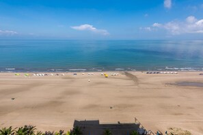 A beach with umbrellas and beach chairs lined up along the shore.