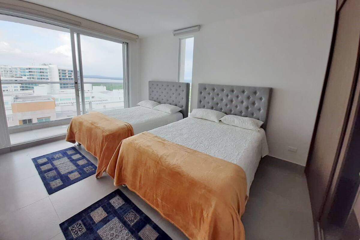 A hotel room with two beds, large windows, and a view of the cityscape.