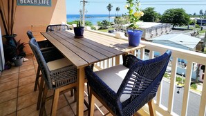 Una mesa y sillas de madera en un balcón con vista al mar.