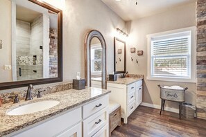 A bathroom with a large mirror, granite countertops, a sink, and a towel rack. - Parkview at Red River (Red River)