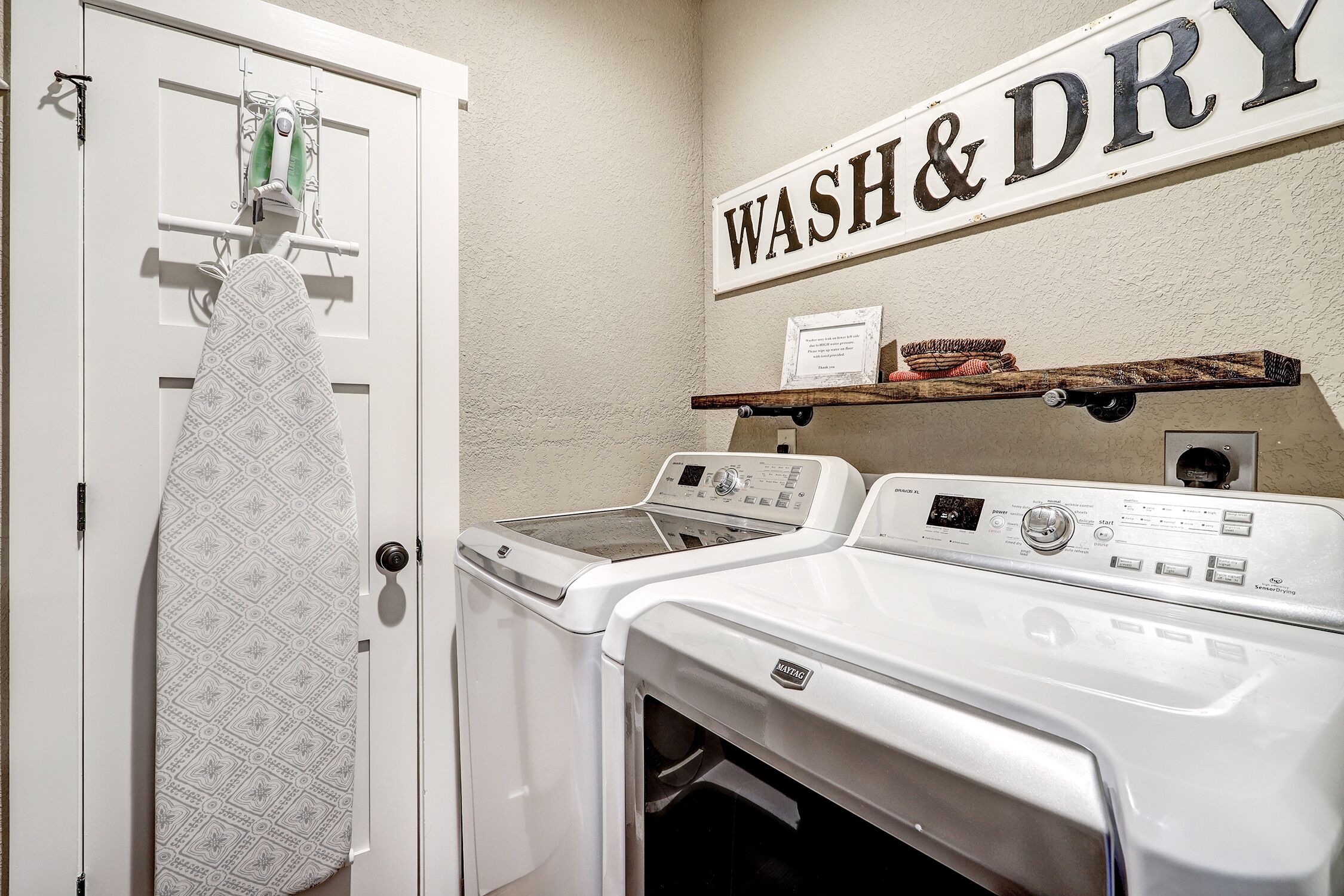 Un área de lavandería con un letrero en la pared que dice "WASH & DRY", un tendedero y una lavadora.