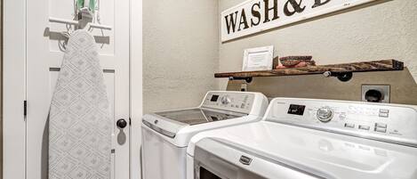 Un área de lavandería con un letrero en la pared que dice "WASH & DRY", un tendedero y una lavadora.
