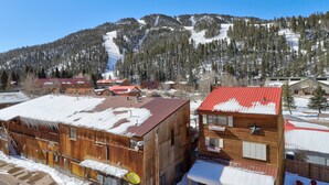 A wooden building with a red roof, surrounded by snow-covered ground and a mountainous backdrop. - Parkview at Red River (Red River)