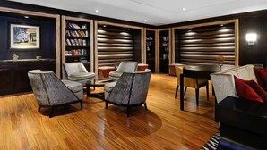 Un salon moderne avec un plancher en bois, une table à manger et deux canapés. Des étagères sont disposées le long des murs et, sur le côté gauche, on peut voir un tableau encadré.