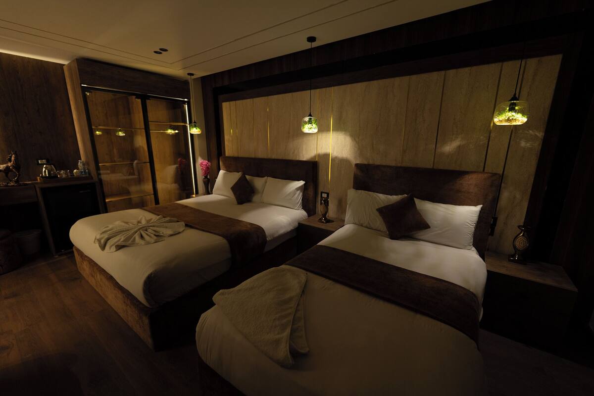 A hotel room with two beds, wooden headboards, and bedside lamps.