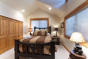 A bedroom with a large bed, wooden wardrobe, two bedside tables with lamps, and a window with blinds. - Five bedroom, five bath near slopes (Whitefish)